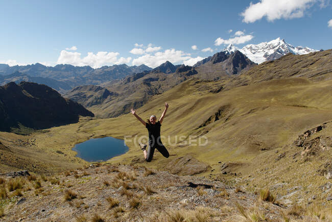 Mujer joven saltando con el lago en la distancia, Lares, Perú - foto de stock
