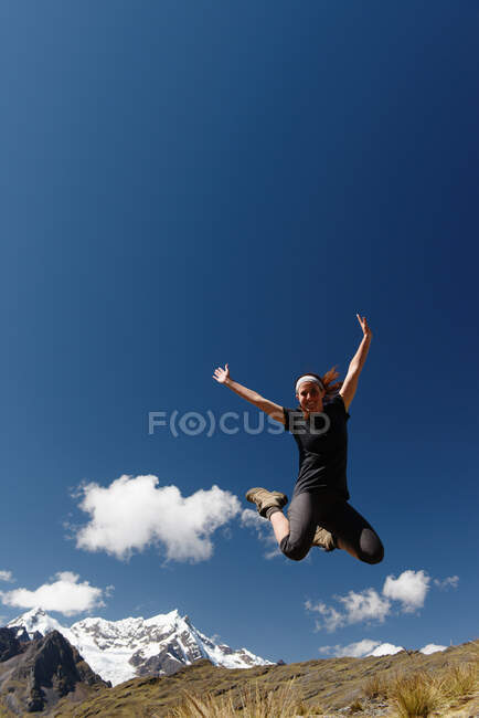 Young woman jumping against clear blue sky, Lares, Peru — Stock Photo