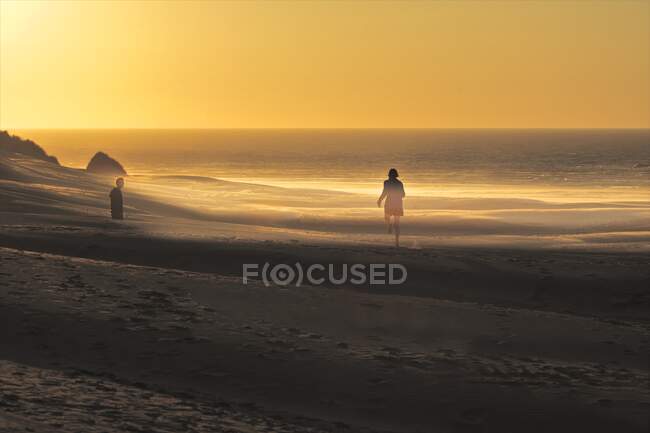 Couple sur la plage à Golden Bay au coucher du soleil, Île du Sud, Nouvelle-Zélande — Photo de stock
