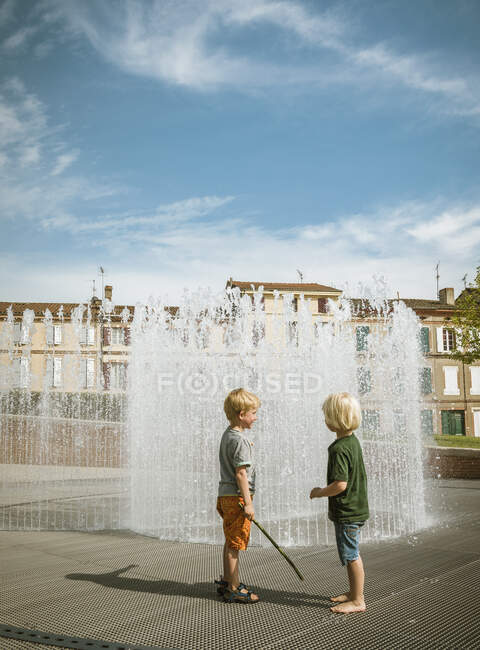 Dos hermanos junto a la fuente del jardín, Palais de la Berbie, Albi, Mediodia Pirineos, Francia - foto de stock