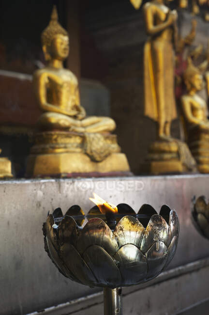 Lampada ad olio accesa davanti alle statue di Buddha a Wat Suthep, Chiang Mai, Thailandia — Foto stock