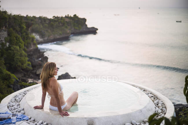 Frau sitzt im Wellness-Pool, Blick aufs Meer, Balangan, Bali, Indonesien — Stockfoto