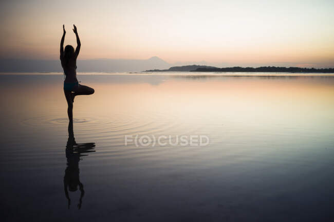 Femme dans la mer, en position yoga, vue arrière, Gili Air, Indonésie — Photo de stock