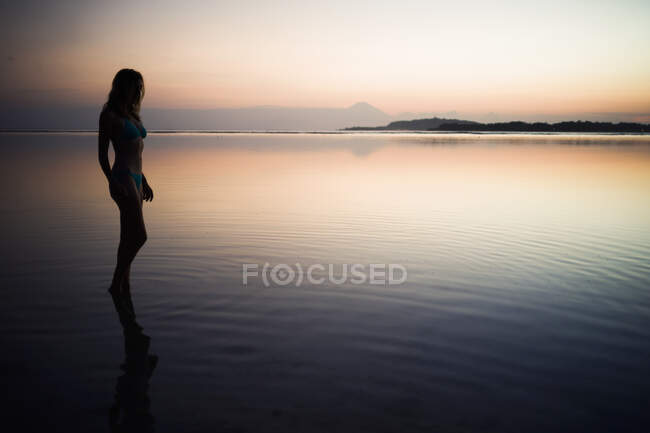 Femme debout dans la mer au coucher du soleil, Gili Air, Indonésie — Photo de stock