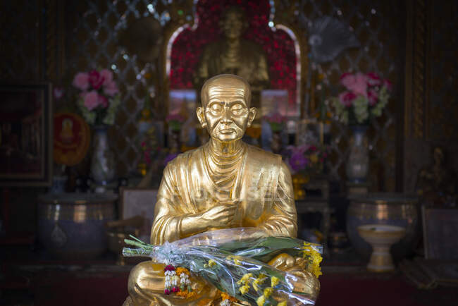 Estátua de buda dourada com flores — Fotografia de Stock