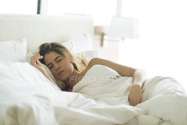 Young woman asleep in hotel bed — Stock Photo