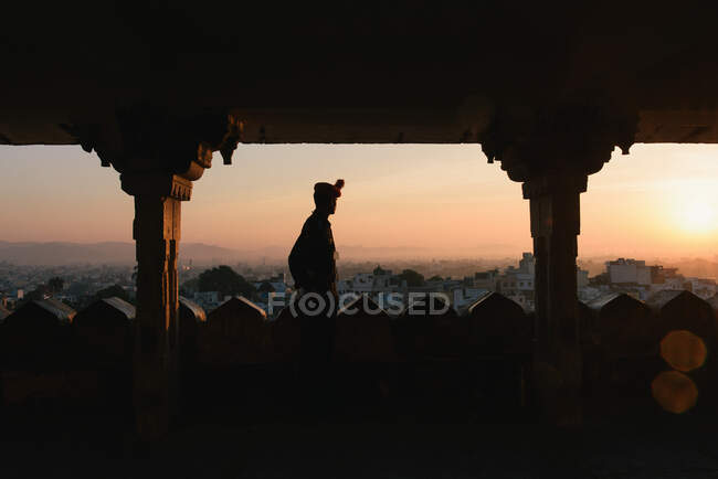 Silhouetted tourist looking out from City Palace at sunset, Lake — Stock Photo