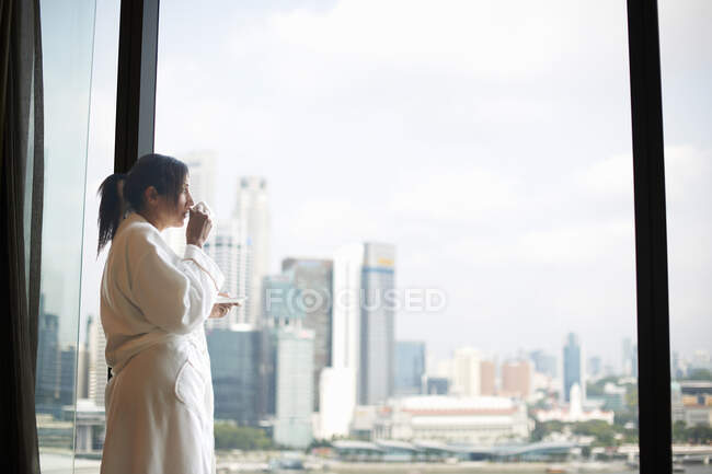Mature female tourist drinking coffee whilst looking out of wind — Stock Photo