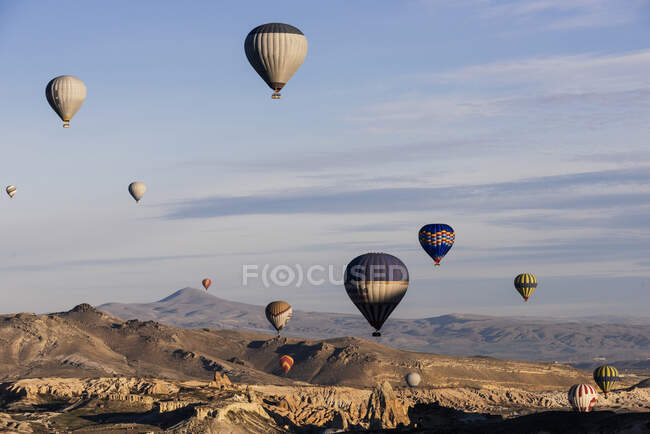 Hot air balloons floating over rock formations at sunrise in the sky — Stock Photo