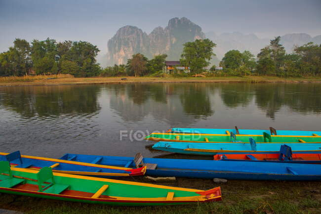 Barcos multicolores amarrados en el río Nam Song, Vang Vieng, Laos - foto de stock