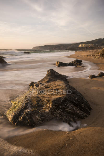 View down beach of tidal waves lapping rocks, Praia do Guincho — Stock Photo