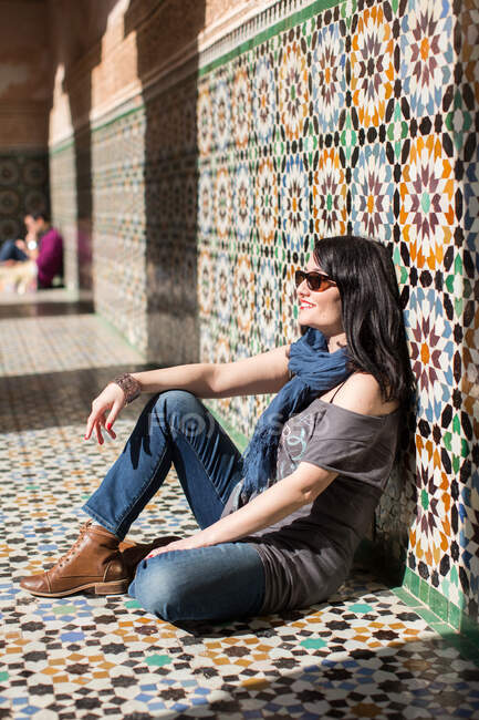 Side view of woman sitting against tiled wall, Ben Youssef Madra — Stock Photo