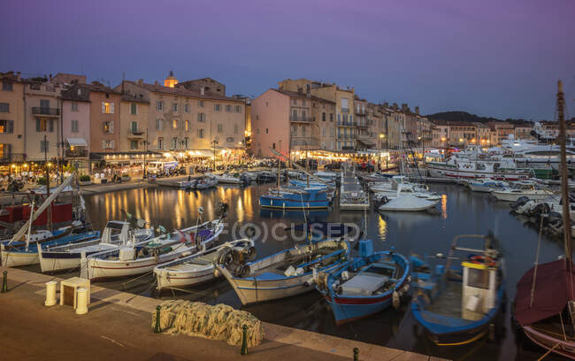 Bateaux de pêche et yachts de luxe dans le port de St Tropez au coucher du soleil — Photo de stock