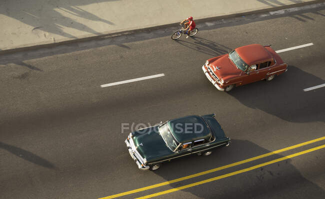 Високий кут огляду велосипедиста і вінтажних автомобілів на Ель-Малекон, Гаван — стокове фото