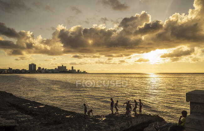 Garçons sur des rochers marins au coucher du soleil, La Havane, Cuba — Photo de stock