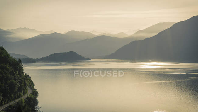 Salida del sol sobre las montañas brumosas, Lago de Como, Italia - foto de stock