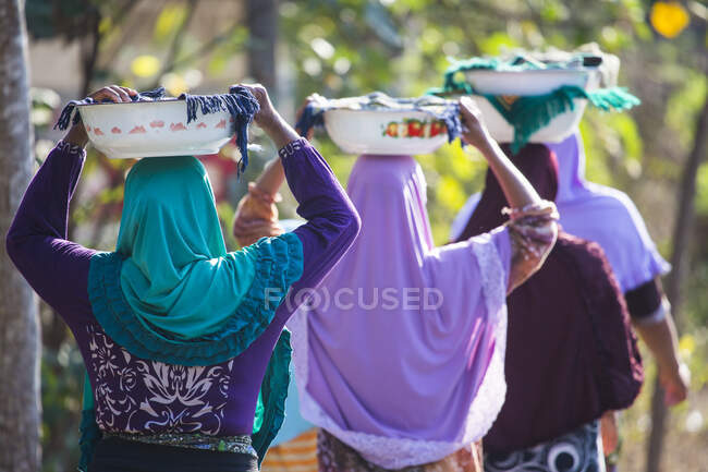 Rear view of muslim women carrying religious offerings on their — Stock Photo