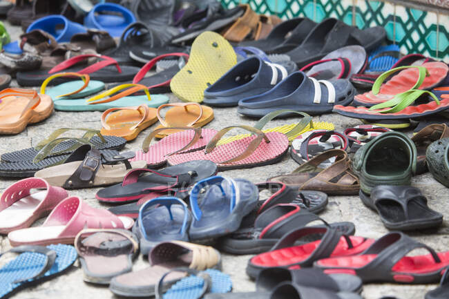 Reihenweise Schuhe und Flip-Flops auf dem Bürgersteig vor der Moschee, — Stockfoto