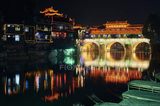 Puente a través del río, iluminado por la noche, Fenghuang, Hunan, China - foto de stock