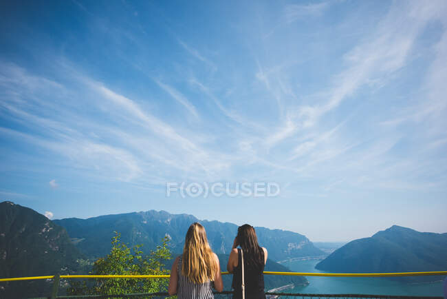 Dos mujeres en el balcón con vistas al lago Lugano, Suiza - foto de stock