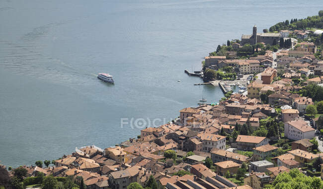 Vista de ángulo alto de ferry acercándose pueblo frente al mar, Lago de Como - foto de stock