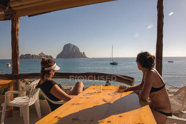 Two female tourists looking over to Es Vedra, Ibiza, Spain — Stock Photo