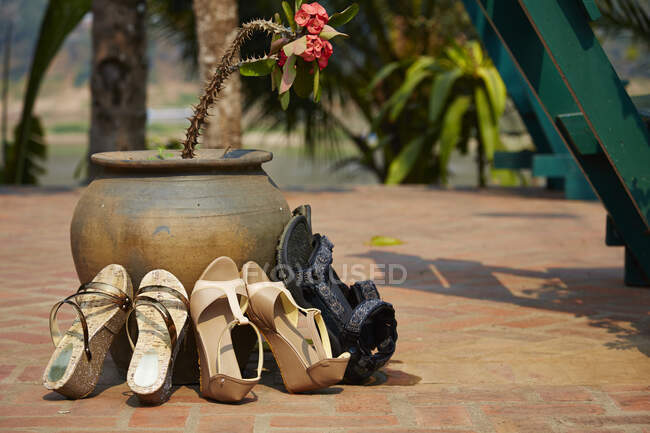Обувь и сандалии опираясь на цветочный горшок, Луанг-Прабанг, Лао — стоковое фото