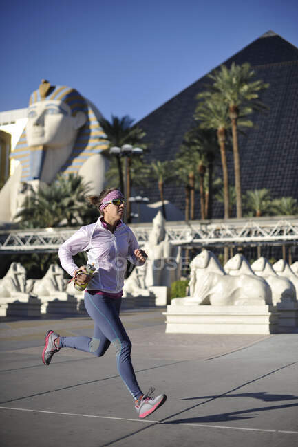 Corredor feminino adulto médio correndo em frente ao hotel pirâmide em las — Fotografia de Stock