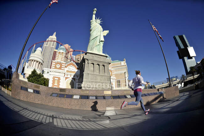 Corredor femenino adulto medio corriendo delante de la estatua de la libertad en - foto de stock