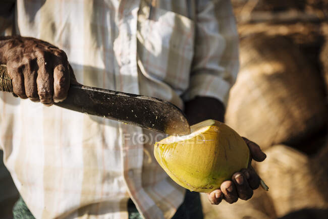Чоловік ріже кокос ножем — стокове фото