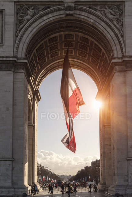 Sonnenbeleuchtete Ansicht der französischen Flagge und des Arc de Triomphe, Paris, Frankreich — Stockfoto
