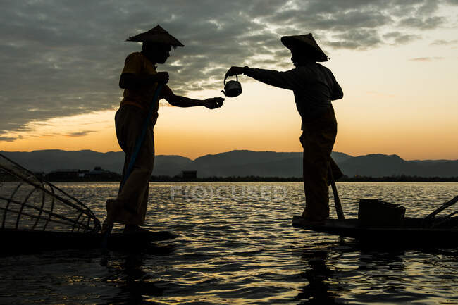 Два рыбака пьют чай в сумерках, озеро Инле, штат Шань, Мьянма — стоковое фото