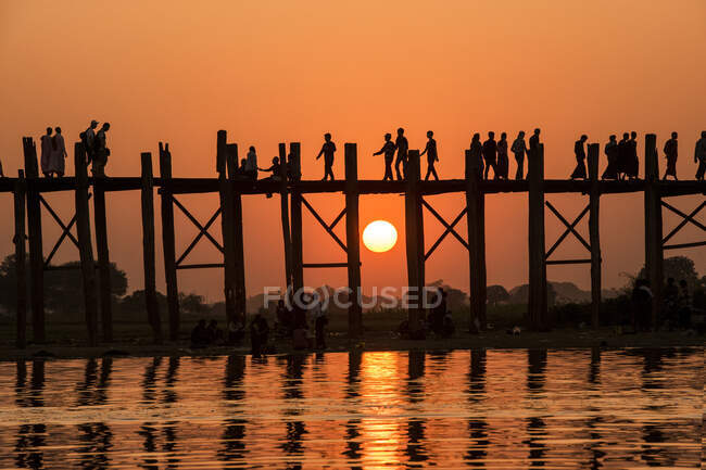 Люди, які йшли через міст Бейн на заході сонця, Амарапура (Мандалай)., — стокове фото