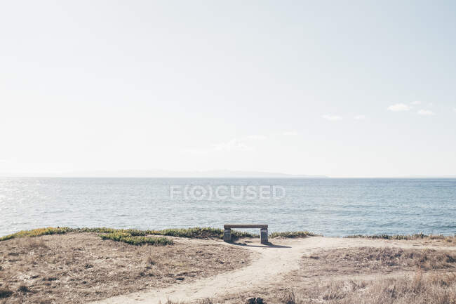 Bench on cliff top overlooking ocean — Stock Photo