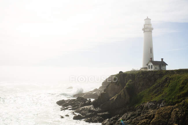 Lighthouse on cliff overlooking ocean — Stock Photo