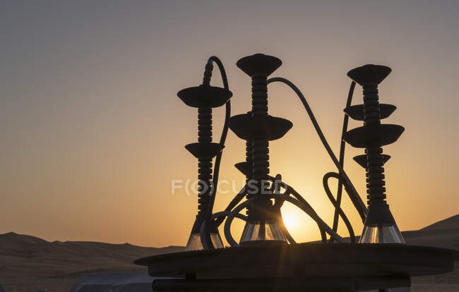 Shishas árabes (tubos de água) em uma mesa no deserto ao pôr do sol — Fotografia de Stock