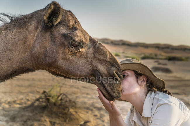 Mujer joven besando camello, Abu Dhabi, Emiratos Árabes Unidos - foto de stock