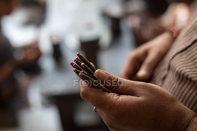 Primer plano de la mano que sostiene rubíes en taller de pulido, Jaipur, R - foto de stock