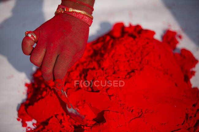 Primer plano de la mano mezclando polvo rojo, Jaipur, Rajasthan, India - foto de stock