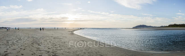 Panoramic image of people on beach at sunset, Tamarindo, Guanaca — Stock Photo