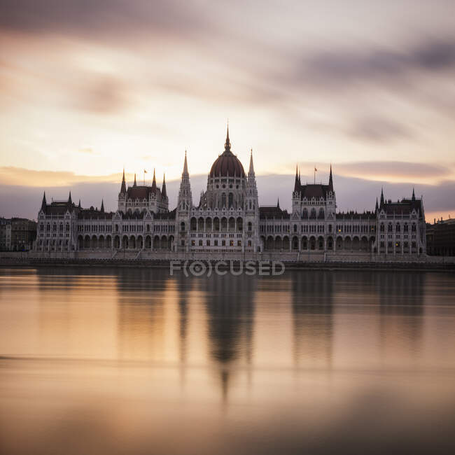 Salida del sol detrás del edificio del Parlamento húngaro y el río Danubio - foto de stock