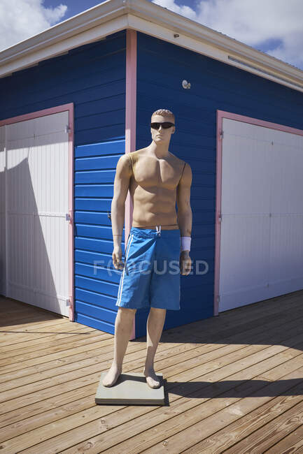 Male mannequin wearing sunglasses and shorts outside beach hut, — Stock Photo