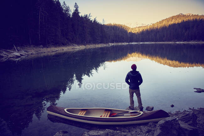 Hombre al lado de la canoa, lago Eibsee en la base de Zugspitze, Garmisch-Par - foto de stock