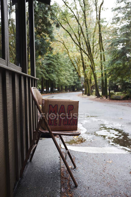 Mapa de retorno, caixa de papelão na cadeira no parque, California, USA — Fotografia de Stock
