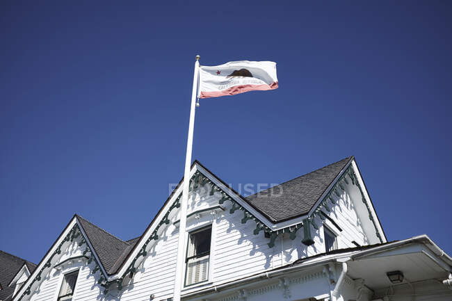 Білий дерев'яний таунхаус і прапор Каліфорнії (США). — стокове фото