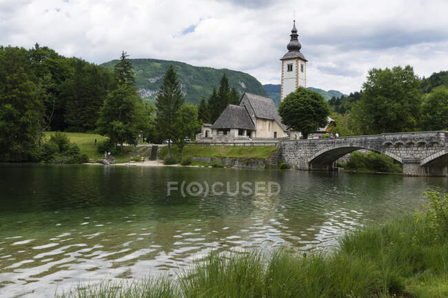 Iglesia de San Juan Bautista y el puente de piedra sobre el lago Boh - foto de stock