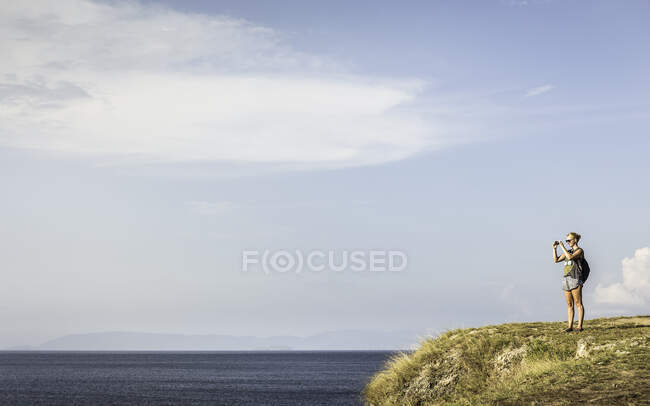 Turista fotografando em penhasco, Lombok, Indonésia — Fotografia de Stock
