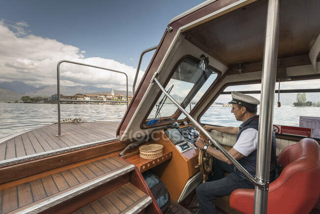 Capitán conduciendo barco de excursión, Lago Maggiore, Isole Borromee, Isola - foto de stock