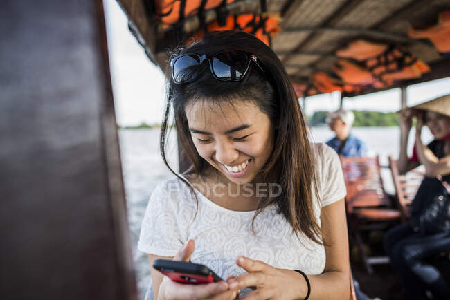 Женщина смотрит на фото в мобильном телефоне на круизной лодке, Mekong De — стоковое фото