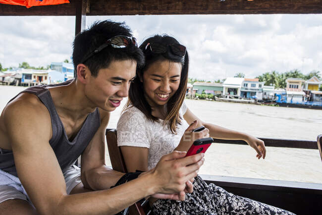 Пара дивиться на фотографію на круїзному човні на мобільному телефоні Меконг Д. — стокове фото